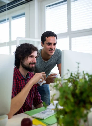 two-male-graphic-designers-holding-crumpled-paper-while-working-computer_1170-965